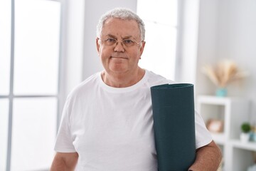 Canvas Print - Middle age grey-haired man smiling confident holding yoga mat at home