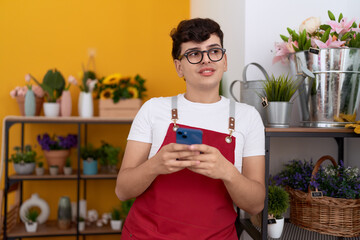 Poster - Non binary man florist smiling confident using smartphone at flower shop