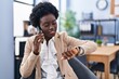 © Krakenimages.com - Young african american woman business worker talking on the smartphone looking watch at office