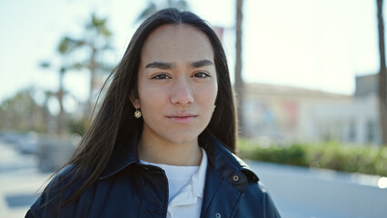 Young beautiful hispanic woman standing with serious expression at street