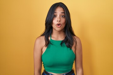 Poster - Brunette woman standing over yellow background afraid and shocked with surprise and amazed expression, fear and excited face.