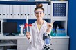 © Krakenimages.com - Teenager girl working at scientist laboratory holding degree smiling happy pointing with hand and finger to the side