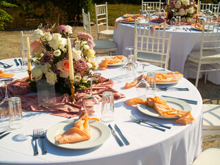 Wall Mural - Beautiful outdoor wedding decoration in city. Candles and dried flowers and accessories with bouquets and glasses on table with linen tablecloth on newlywed table on green lawn