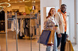 © Roman - joyful young people in love or family with paper bags in hands while walking during shopping in the mall, close up photo. copy space.