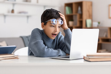 Poster - Surprised little boy in eyeglasses using laptop at home