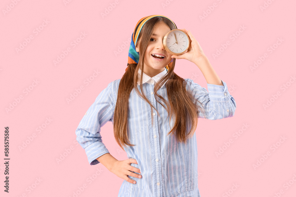 Little girl with alarm clock on pink background