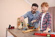 © New Africa - Father and son screwing wheels to wooden plank indoors. Repair work