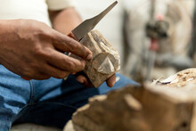 Hands Of Older Latino Man Carving A Jaguar In Wood With Knife With A Lot Of Passion