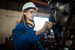 Woman worker operating a machine tool in metal factory.
