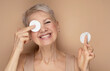 Beautiful elderly 60s woman with short hair doing her everyday routine removing her makeup with cotton pad