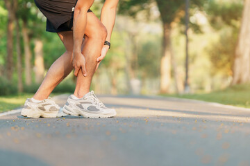 Wall Mural - Young adult man with his muscle pain during running. runner man having leg ache due to Calf muscle pull. Sports injuries and medical concept