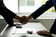 © ArLawKa - The salesman shakes hands with the customer after signing the contract and completing the payment. A car dealer or sales manager offers to sell a car and explains the insurance terms in the office.