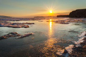 Wall Mural - Scenic spring seascape of ice drift on Baikal Lake at sunrise. View on Small Sea at May early morning. Natural background. Spring travel, hiking and active outdoors