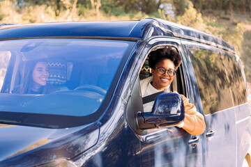 Joyful women on nomadic road trip adventure in camper van, concept of female friendship and travel, copy space for text