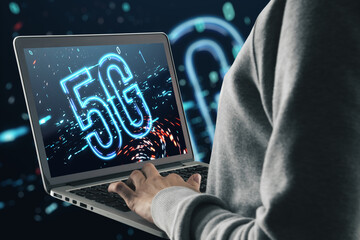 Poster - Close up of hands using laptop with 5G icon on screen and on blurry dark background. Internet, 5G network connection and speed concept.