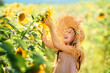 Little pretty girl having fun playing among field sunflowers. Child hug blooming sunflower. Hello summer concept.