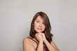 © artmim - Close up studio shot of beautiful young brunette woman model with curly hair looking at camera with charming cute smile while posing against white studio wall background