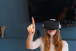 © Westend61 - Woman wearing virtual reality headset gesturing at home