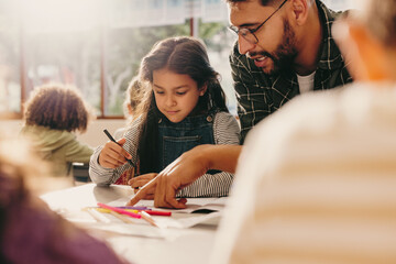 Wall Mural - Teacher giving guidance in an art class. Male educator shows a student how to draw