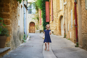 Adorable preschooler girl walking on a street of Medieval village of Lourmarin in Southern France