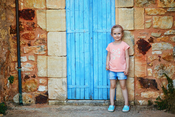 Wall Mural - preschooler girl having fun near brick wall in Roussillon, Provence, Southern France