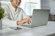 © bongkarn - Cropped image of a handsome Asian businessman using his laptop at his desk.