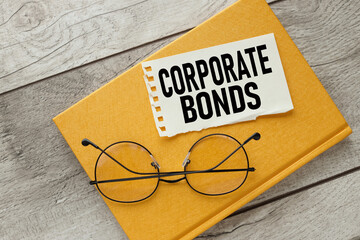 Wall Mural - CORPORATE BONDS torn paper on a yellow notebook. near glasses.