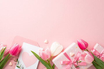 Wall Mural - Mother's Day celebration concept. Top view photo of gift boxes with bows envelope with postcard fresh flowers tulips and small hearts on isolated pastel pink background with blank space