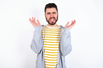 Wall Mural - Indignant Young caucasian mán wearing trendy clothes over white background gestures in bewilderment, frowns face with dissatisfaction.