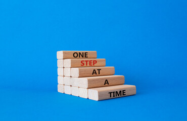 Wall Mural - One step at a time symbol. Concept words One step at a time on wooden blocks. Beautiful blue background. Business and One step at a time concept. Copy space.