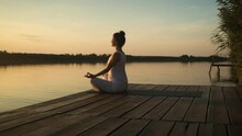 Pregnant Woman Doing Yoga At Lake During Sunset.