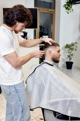 Wall Mural - Barber trim hair with clipper on handsome bearded man