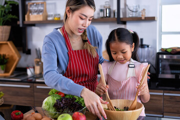 Wall Mural - Young mother teach daughter in the kitchen learn online cooking clean food from the laptop computer