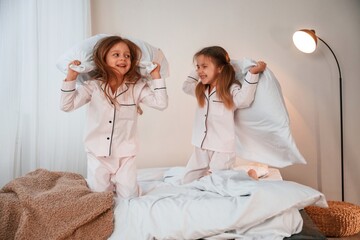 Active weekend. On the bed with pillows. Two little girls are playing and having fun together in domestic room