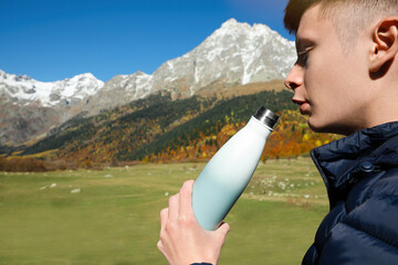 Sticker - Boy drinking from thermo bottle in mountains on sunny day. Space for text