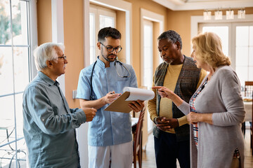 Wall Mural - Young healthcare worker analyzing medical data with group of seniors in nursing home.