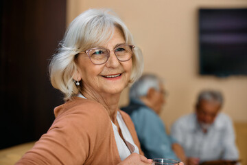 Wall Mural - Portrait of happy senior woman day dreaming in residential care home.