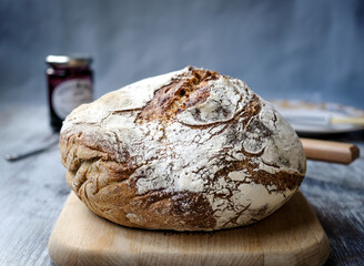 Freshly baked sourdough bread on a wooden board with jam