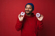 © Drobot Dean - Indian man eating donuts isolated over red background