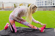 Stretching before running. The athlete is warming up at the stadium outside. A model in a bright tracksuit with an upbeat mood