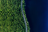 Fototapeta Na ścianę - Aerial view of road in green woods and blue lakes water in Finland