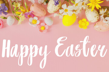 Happy Easter text sign on stylish eggs and blooming flowers on pink background flat lay. Modern Easter greeting card. Handwritten lettering