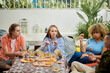© DragonImages - Group of young people eating snacks and drinking beer when hanging out together
