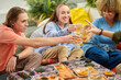 © DragonImages - Group of young people toasting with glasses of beer over table with snacks