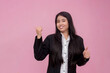 © Mdv Edwards - A friendly woman points to the left while giving a thumbs up gesture. Recommending a service or product. Isolated on a pink background.