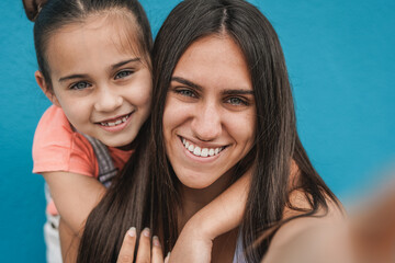 Wall Mural - Happy teenage girl taking a selfie with her little sister outdoor - Youth culture concept