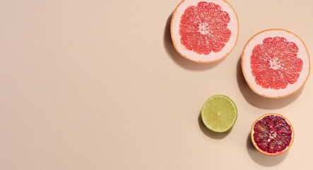 Wall Mural - Sliced pieces of orange, lime and grapefruit on a beige background, top view