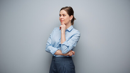 Wall Mural - Portrait of serious thinking business woman on gray background looking away.