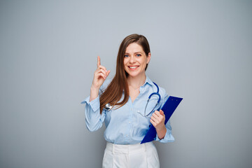 Wall Mural - Smiling doctor woman pointing finger up,  isolated portrait with copy space.