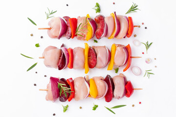 Wall Mural - Uncooked mixed meat skewer with peppers.Raw chicken leg meat skewers with vegetables,plums,peppers,onions, on a white background.Skewers with pieces of raw meat, red, yellow and green pepper.Top view.